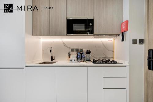 a kitchen with white cabinets and a microwave at Mira Holiday Homes-Cozy studio close to metro in Dubai
