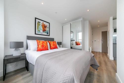 a bedroom with a large white bed with orange pillows at Modern and Bright Studio in Central East Grinstead in East Grinstead