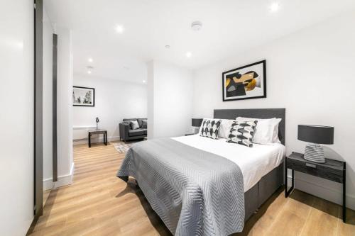a white bedroom with a bed and a chair at Modern and Stylish Studio Apartment in East Grinstead in East Grinstead