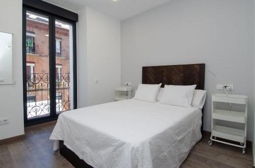 sypialnia z dużym białym łóżkiem i oknem w obiekcie We Madrid Casa Duque w Madrycie