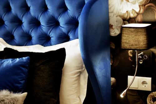 a bedroom with a blue bed with pillows and a lamp at Broadway Residence in Budapest