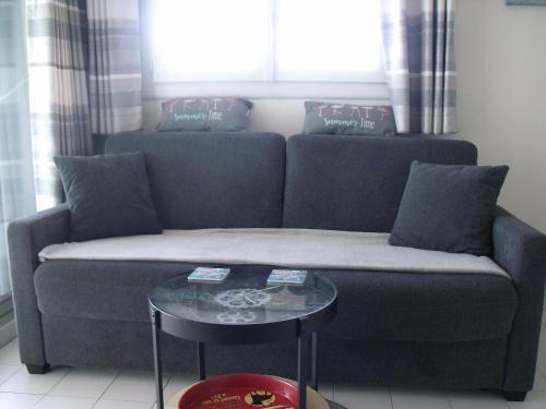- un canapé avec des oreillers et une table devant une fenêtre dans l'établissement Appartement T2, 7 JOURS MINIMUM, Climatisé, 3 étoiles, 40m2 ,parking privé, Mer 300m, Wifi, Piscines, très propre, Ascenseurs, en étage, au Grau-du-Roi
