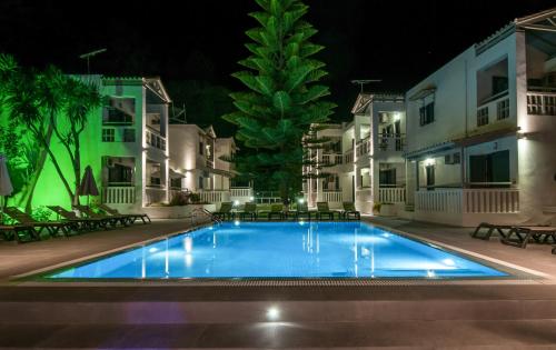 a swimming pool in front of some buildings at night at Trianon Studios in Tsilivi