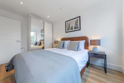 Contemporary 1 Bedroom Apartment in East Grinstead في إيست غرينستيد: غرفة نوم بسرير وطاولة مع مصباح
