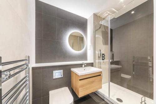La salle de bains est pourvue d'un lavabo, d'une douche et d'un miroir. dans l'établissement Spacious and Bright Studio in East Grinstead, à East Grinstead