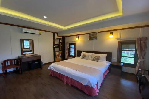 a bedroom with a large bed and a desk at Phu Ing Fah Resort in Chiang Mai