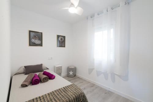 a white bedroom with a bed with purple pillows at Quimanna Calafell Beach in Calafell