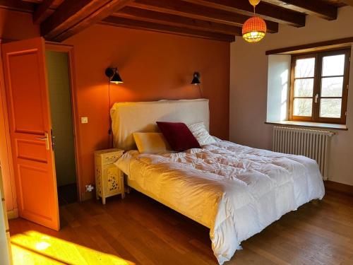a bedroom with a large bed with orange walls at Les Janets 12 personnes in Saint-Sauveur-en-Puisaye