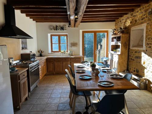 a kitchen with a wooden table with chairs and a dining room at Les Janets 12 personnes in Saint-Sauveur-en-Puisaye