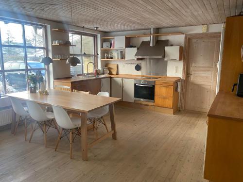 a kitchen with a wooden table and white chairs at Spacious 3-bedroom house in Hjørring