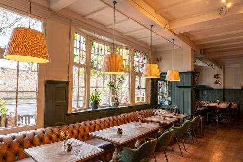 una fila de mesas en un restaurante con grandes ventanas en The William en Londres