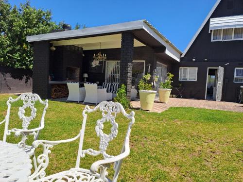 two white chairs sitting in front of a house at Milky Way Executive Suite in Sandbaai