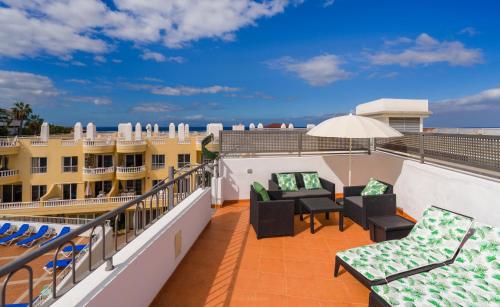 a balcony with chairs and tables and an umbrella at Poseidón Arena Beach in Puerto de Santiago
