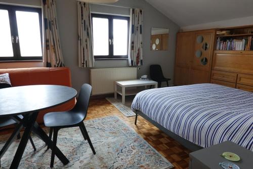 - une chambre avec un lit, une table et des chaises dans l'établissement Logeren in Aldeneik, à Maaseik