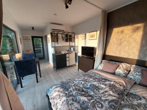 a bedroom with a bed and a desk and a kitchen at Stüble Kabinok in Somogyhárságy