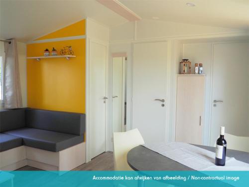 Habitación con cama y botella de vino en Siblu camping Lauwersoog, en Lauwersoog