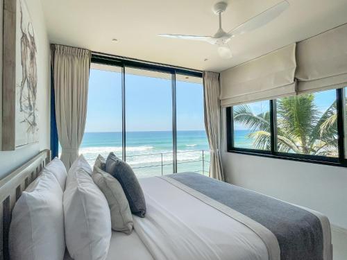 a bedroom with a bed with a view of the ocean at DORMERO Hotel Sri Lanka Hikkaduwa Beach in Hikkaduwa