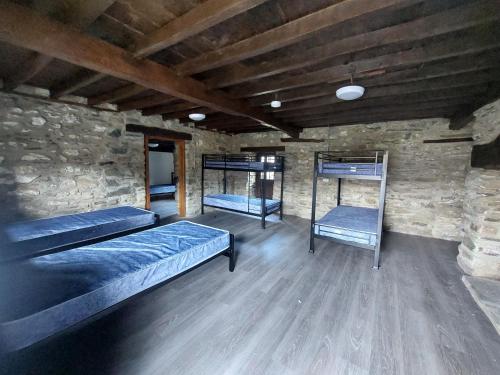 a room with two beds and a stone wall at Cwm Clyd Longhouse in Llanwrthwl