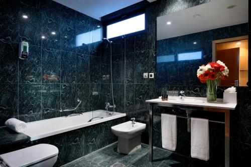 a bathroom with a toilet and a tub and a sink at Hotel SB Icaria in Barcelona