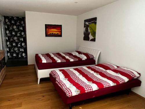 2 Betten in einem Zimmer mit roten und weißen Decken in der Unterkunft Studio an traumhafter Lage in Sigriswil