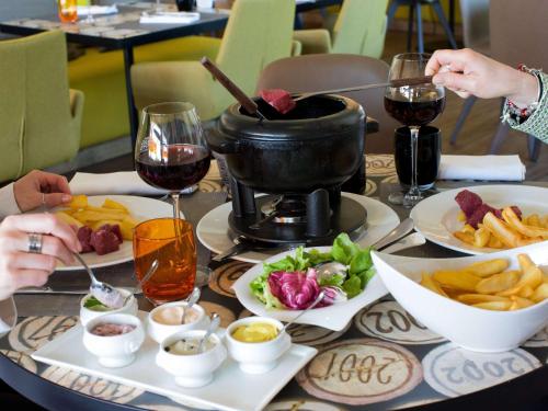 une table recouverte de assiettes de nourriture et de verres de vin dans l'établissement ibis Beaune La Ferme Aux Vins, à Beaune