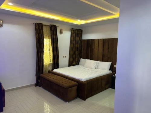 1 dormitorio con cama y banco. en Valentino Swiss Hotel and Apartment, en Port Harcourt
