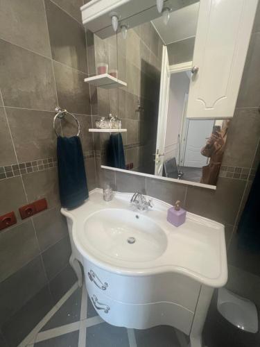 een badkamer met een witte wastafel en een spiegel bij Location d’appartement in Nice