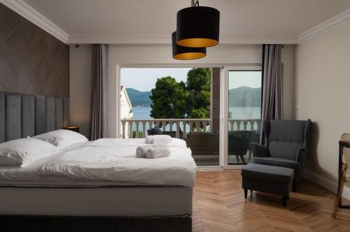 a bedroom with a bed and a chair and a large window at Villa Suartini Viganj Pool or Jakuzzi in Viganj