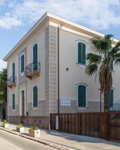 a white building with a fence and a palm tree at Luxury Liberty House in Alghero