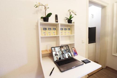 a laptop computer sitting on a white desk at Hotel Ulm Zentrum - Komplettes Zimmer, Hochbett, Android TV & eigenem Bad - perfekt für Familien & Gruppen in Ulm