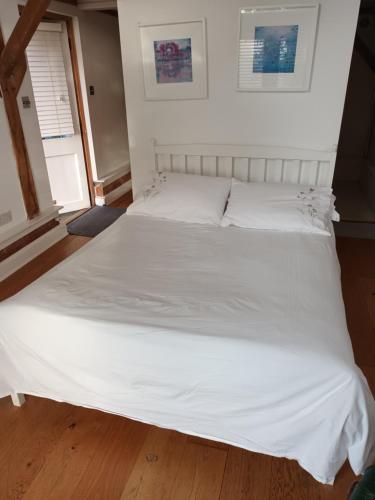 a large white bed with white sheets and pillows at LITTLE OAK - Kingsize Double Oak Studio - Sleeps 2 - Quirky - Rural in Haslemere