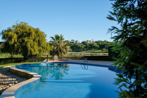 a swimming pool with trees in the background at Quinta do Lago Golfside Retreat in Quinta do Lago