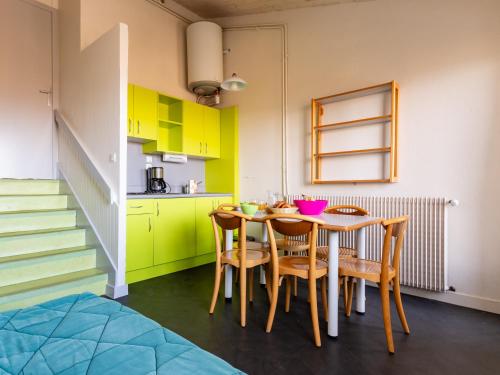 une cuisine avec des armoires jaunes et une table avec des chaises dans l'établissement Vacancéole - Les Monts du Forez, à Saint-Jean-la-Vêtre