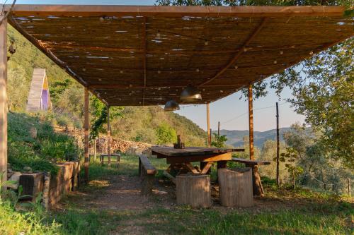 una mesa de picnic de madera bajo un techo de madera en tendù family, en Chiusanico