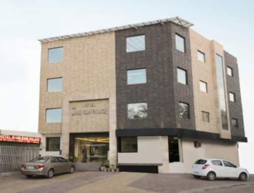 a building with two cars parked in front of it at Hotel Mani Ram Palace,Agra in Agra