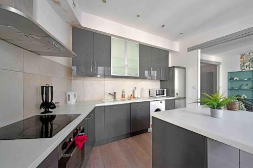 a large kitchen with gray cabinets and white appliances at Pops Flat - Parking privé gratuit - Wi-Fi - AC Clim in Avignon