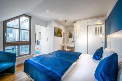 ein Schlafzimmer mit einem blauen Bett und einem großen Fenster in der Unterkunft Hotel Rivoli in München