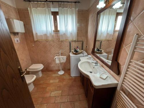 een badkamer met een wastafel, een toilet en een spiegel bij Casina di Pacina in Abbadia di Montepulciano