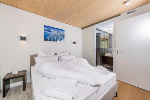 a white bedroom with a large bed with white sheets at Luxury architecture chalet with view and wellness in Bludenz