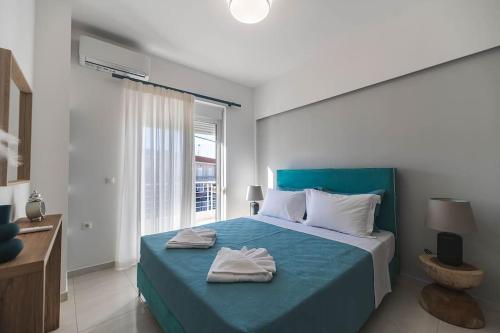 Un dormitorio con una cama azul con toallas. en Archangelos SKY Garden Apartment en Archangelos