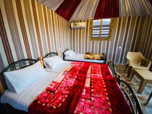 a bedroom with a bed with a red blanket on it at Scarlet Luxury Camp Wadi Rum in Wadi Rum