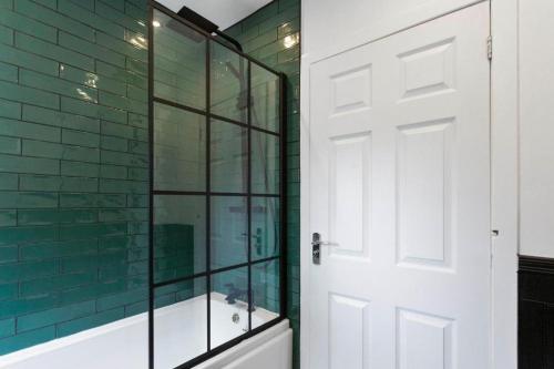 a bathroom with a glass shower and a white door at Stylish 3 bed Edinburgh Abode - Parking and Garden in Edinburgh