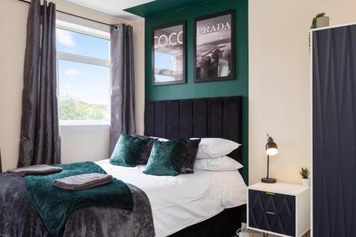 a bedroom with a bed with green walls and a window at Stylish 3 bed Edinburgh Abode - Parking and Garden in Edinburgh