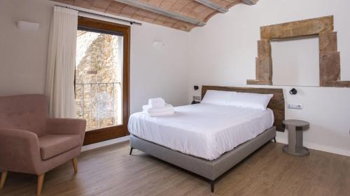 a bedroom with a bed and a chair and a window at Abbatissa Hotel Restaurant in Sant Joan de les Abadesses