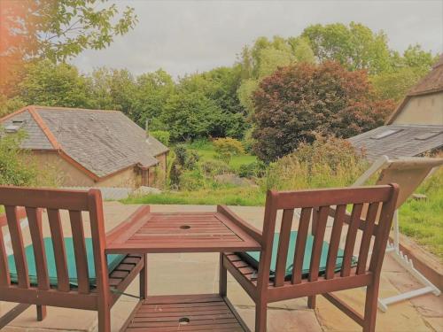 een houten tafel en 2 stoelen op een patio bij The Hide at Lemons Farm in Atherington