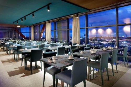 a restaurant with tables and chairs and a view of the city at Hyatt Regency Barcelona Tower in Hospitalet de Llobregat