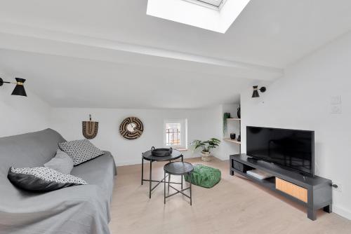 a living room with a couch and a flat screen tv at Le Blackwood in Mazamet