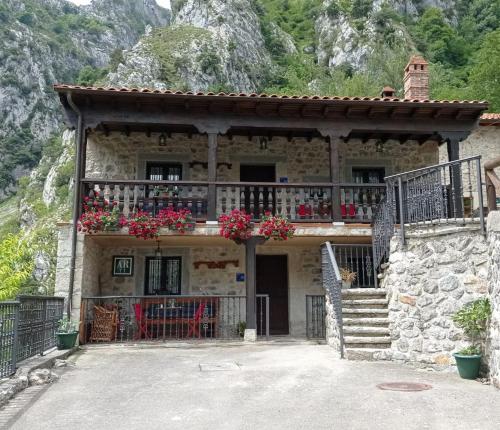 a stone house with a balcony with flowers on it at El Portal del Abuelo in Arenas de Cabrales