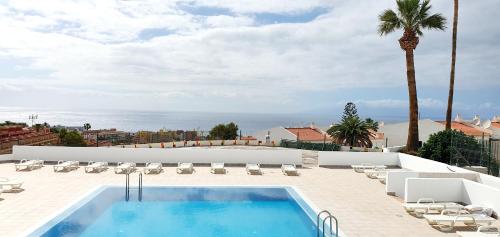 una piscina sul tetto di un edificio con sedie e una palma di Ocean View Apartments ad Adeje