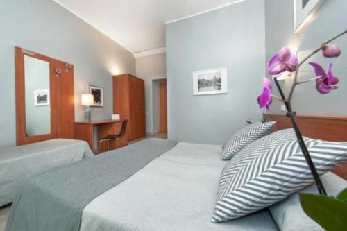 sypialnia z łóżkiem z poduszkami i kwiatem w obiekcie Hotel Reyes w Rzymie